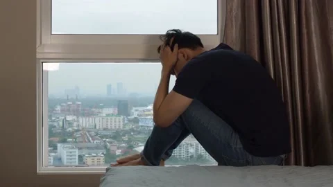 Man crying and covering head at the window Stock Footage 100459502