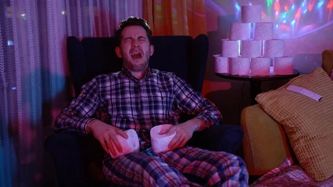 Man is crying and sitting on chair next to a lot of toilet paper Stock Footage 128312802