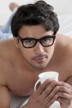 Man with a cup of coffee in bed Stock Photos