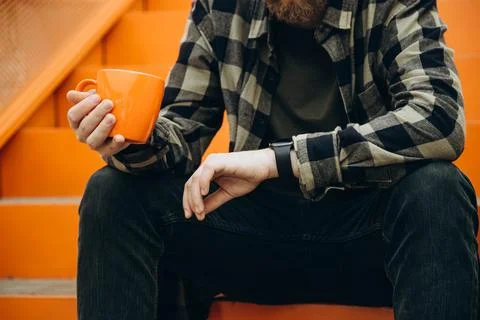 Man with cup of coffee checking time on her smart watch during coffee break. Stock Photos