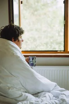 A man with  a cup of coffee looking at the window Stock Photos