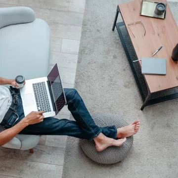 Man with a Cup of coffee using a laptop while sitting on the sofa Stock Photos