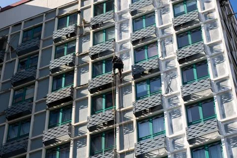 A man is currently in the process of climbing up the side of a building Stock Photos