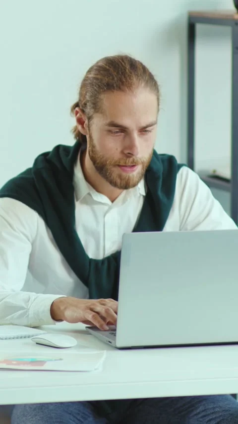A man is currently sitting at a desk while using a laptop computer Stock Footage 305980814