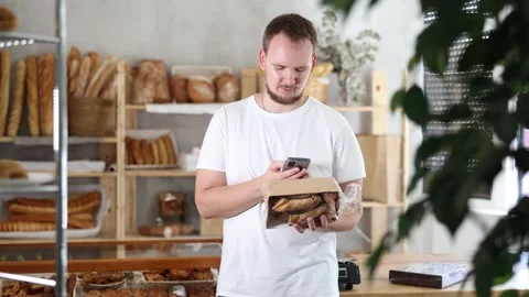Man customer at bakery scans QR code on cookie package using phone camera Stock Footage 308753039