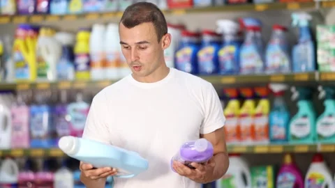 Man customer in store chooses package of laundry detergent Stock Footage 316114645