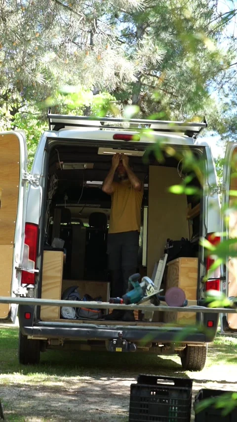 Man customizing a camper van fixing a skylight Stock Footage 274070708