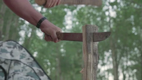 A man cut a log with a knife striking it with a stick. Stock Footage 142188554