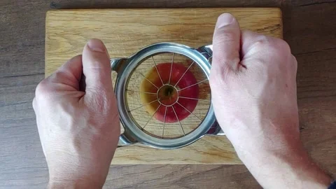 A man cuts an apple into small pieces using a manual apple cutter Stock Footage 162688434