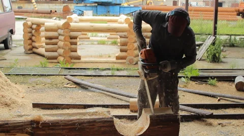 Man cuts off beam chainsaw for future home. Construction works with a wooden Stock Footage 65205345