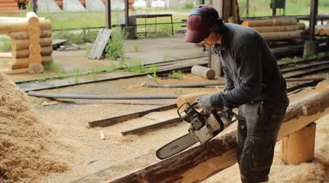 Man cuts off beam chainsaw for future home. Construction works with a wooden Stock Footage 65205386