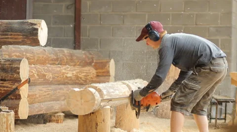 Man cuts off beam chainsaw for future log cabin. Construction works with a Stock Footage 65205419