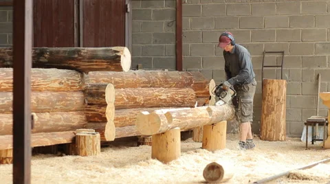 Man cuts off beam chainsaw for future log cabin. Construction works with a Stock Footage 65205433