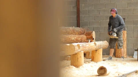 Man cuts off beam chainsaw for future log cabin. Construction works with a Stock Footage 65205438