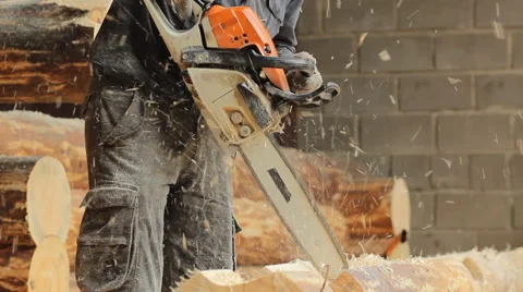 Man cuts off beam chainsaw for future log cabin. Construction works with a Stock Footage 65205451