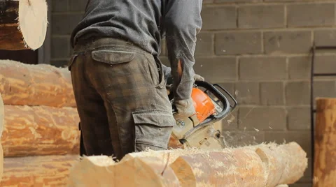 Man cuts off beam chainsaw for future log cabin. Construction works with a Stock Footage 65205459