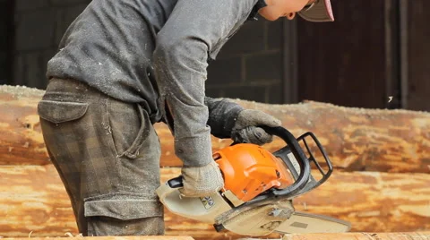 Man cuts off beam chainsaw for future log cabin. Construction works with a Stock Footage 65205480