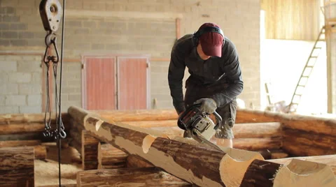 Man cuts off beam chainsaw for future home. Construction works with a wooden Stock Footage 65205512