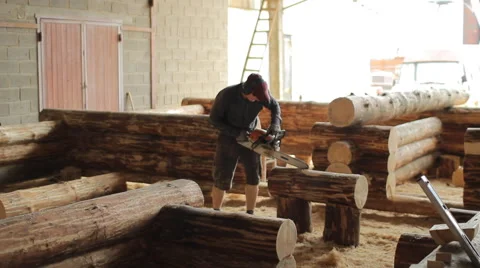 Man cuts off beam chainsaw for future home. Construction works with a wooden Stock Footage 65316105