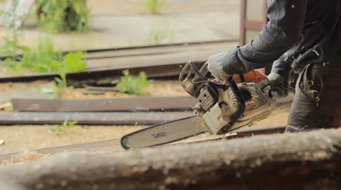 Man cuts off beam chainsaw for future home. Construction works with a wooden Stock Footage 65316660