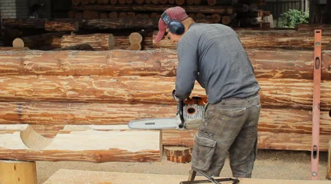 Man cuts off beam chainsaw for future home. Construction works with a wooden Stock Footage 65414575