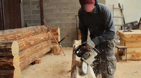 Man cuts off beam chainsaw for future home. Construction works with a wooden Stock Footage 65414616