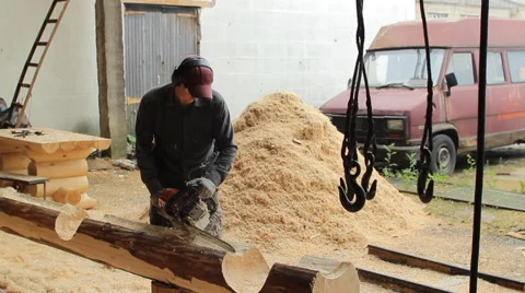 Man cuts off beam chainsaw for future home. Construction works with a wooden Stock Footage 65414628