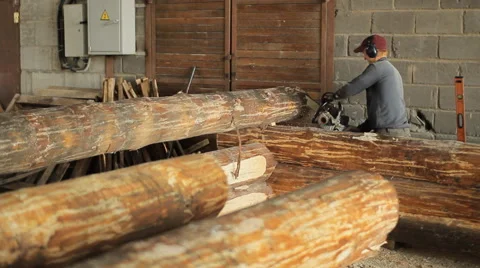 Man cuts off beam chainsaw for future home. Construction works with a wooden Stock Footage 65414666