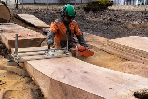 A man cuts boards using a mobile chainsaw mill. Stock Photos