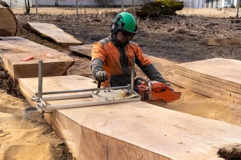 A man cuts boards using a mobile chainsaw mill. Stock Photos