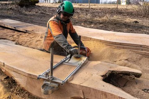 A man cuts boards using a mobile chainsaw mill. Stock Photos