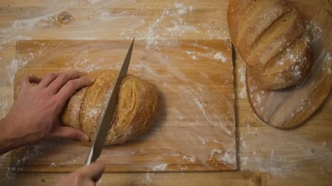 A man cuts bread in the kitchen. Slice the bread to make a sandwich. Top view. W 스톡 동영상 148130932