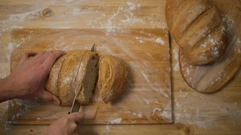 A man cuts bread in the kitchen. Slice the bread to make a sandwich. Top view. W Stock Footage 148131953