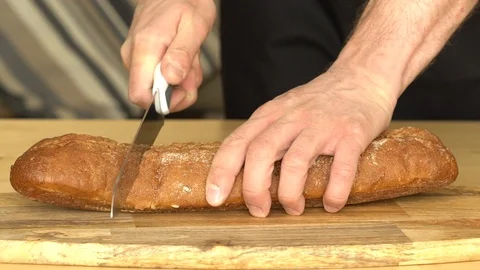Man cuts bread with a knife in slow motion Stock Footage 86933296