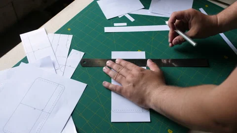 A man cuts a bum, preparing patterns for sewing a product from leather. Uses a 스톡 동영상 198497618