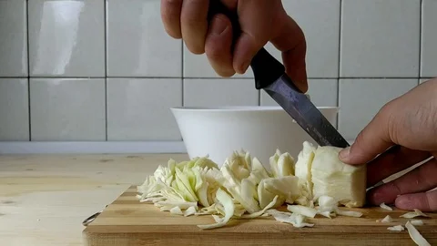 A man cuts cabbage and puts it in a salad bowl Video stock 129845318