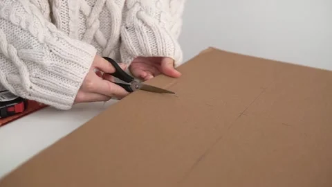 The man cuts the cardboard sheet with scissors Stock Footage 142931955
