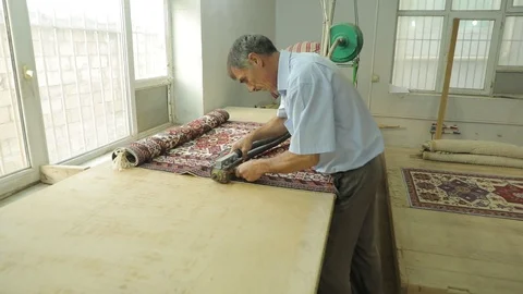 A man cuts a carpet with a special machine. Production of handmade carpets Stock Footage 121931365