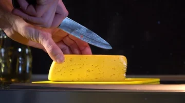 Man cuts cheese with a knife on a cutting board Stock Footage 86155987