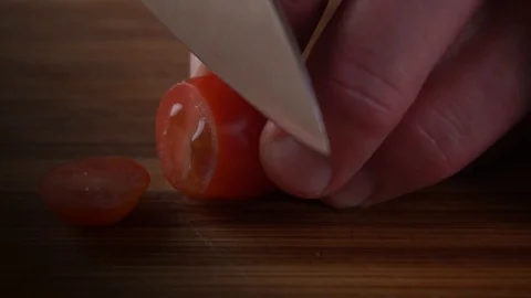 A man cuts a cherry tomato with a chef's knife Video stock 102218320