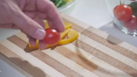 A man cuts a cherry tomato with a knife on a divided board. Stock Footage 103444396