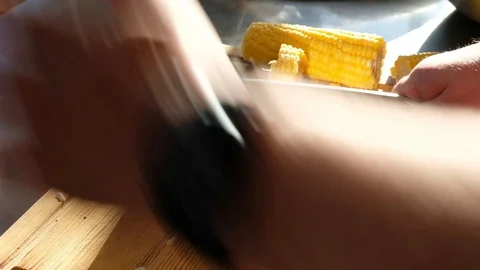 A man cuts corn with a large kitchen knife on a cutting board Stock Footage 91194652