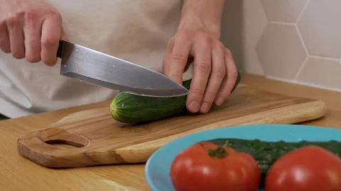 A man cuts a cucumber on a chopping Board 動画素材 129056022