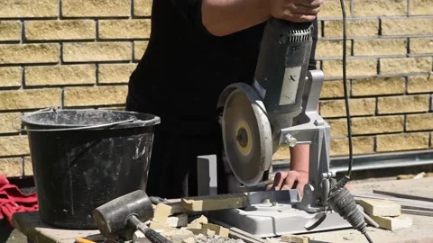 Man cuts a decorative brick with angle grinder on a special stand. Cladding wall Video stock 153927627
