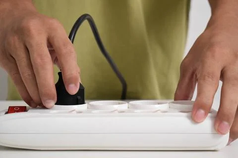 A man cuts off the electric current at a white electrical socket Stock Photos
