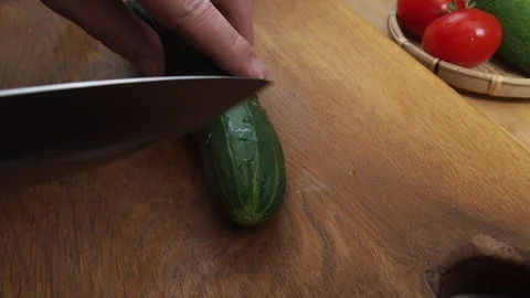 The man cuts off the ends of the cucumber on both sides. wooden cutting Board Stock Footage 129844585