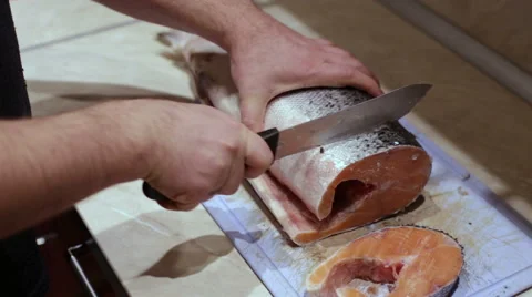 Man cuts the fish steaks on the kitchen table Video stock 57664652