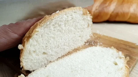 A man cuts fresh bread with a knife on a wooden Board in the kitchen, super slow Stock Footage 117588357