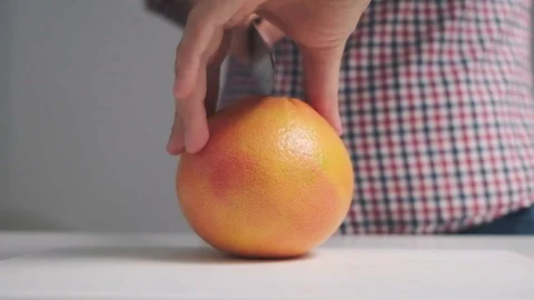 A man cuts a grapefruit into pieces. Grapefruit drops to the floor in pieces. A Stock Footage 120845019