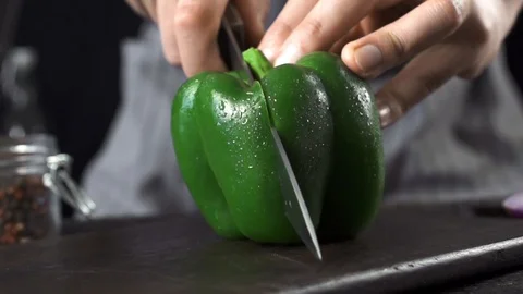 Man cuts green bell pepper with a knife on a wooden board 스톡 동영상 105075376